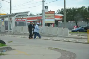 Three people crossing the street at the light rail tracks in Near Northside.