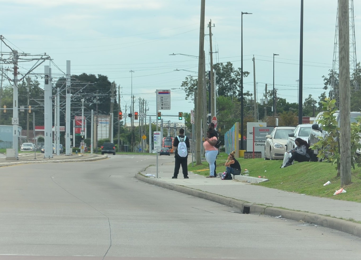 A group of students waiting on the bus near the Houston Community College Northline Campus. There is no bus shelter or any other amenity at the bus stop.