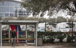"A man waits at a bus stop along Main Street next to the a Federal Emergency Management Agency COVID-19 vaccination super site at NRG Park Wednesday, Feb. 24, 2021 in Houston. Despite being one of the most transit-friendly locations in the region with access to light rail and bus service, walk-ups are not part of the plan presently at the site that opened Wednesday in coordination with the FEMA.Brett Coomer/Staff photographer"