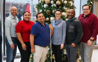 LINK Houston staff standing in front of a christmas tree in their lobby.