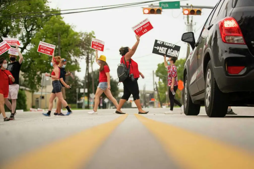 "Desiree Alejandro holds up a sign urging people to "Stop TXDOT" while crossing a crosswalk during a demonstration at the intersection of Polk Street and St. Emmanuel Street just east of downtown Houston in 2020. Mark Mulligan, Houston Chronicle / Staff photographer"